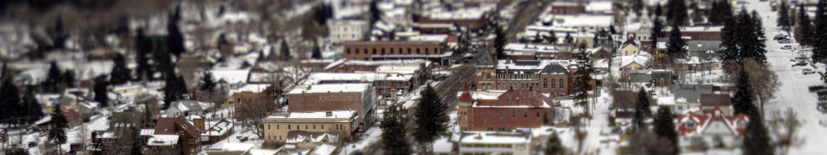Aerial view of a snow-covered Ouray with buildings, streets, and trees; the center is in focus while the edges are blurred.